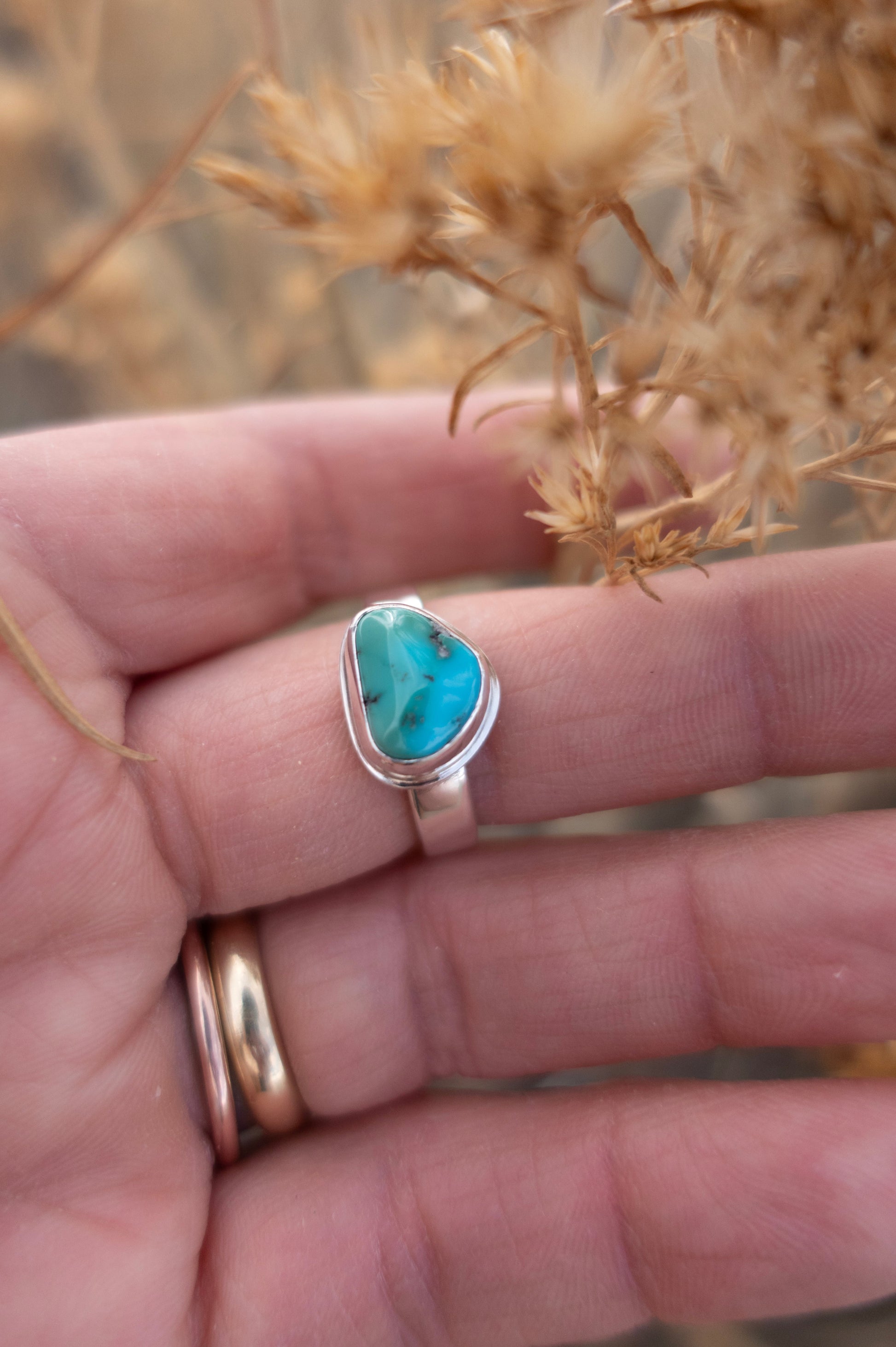 Turquoise ring on a hand with blurred natural background