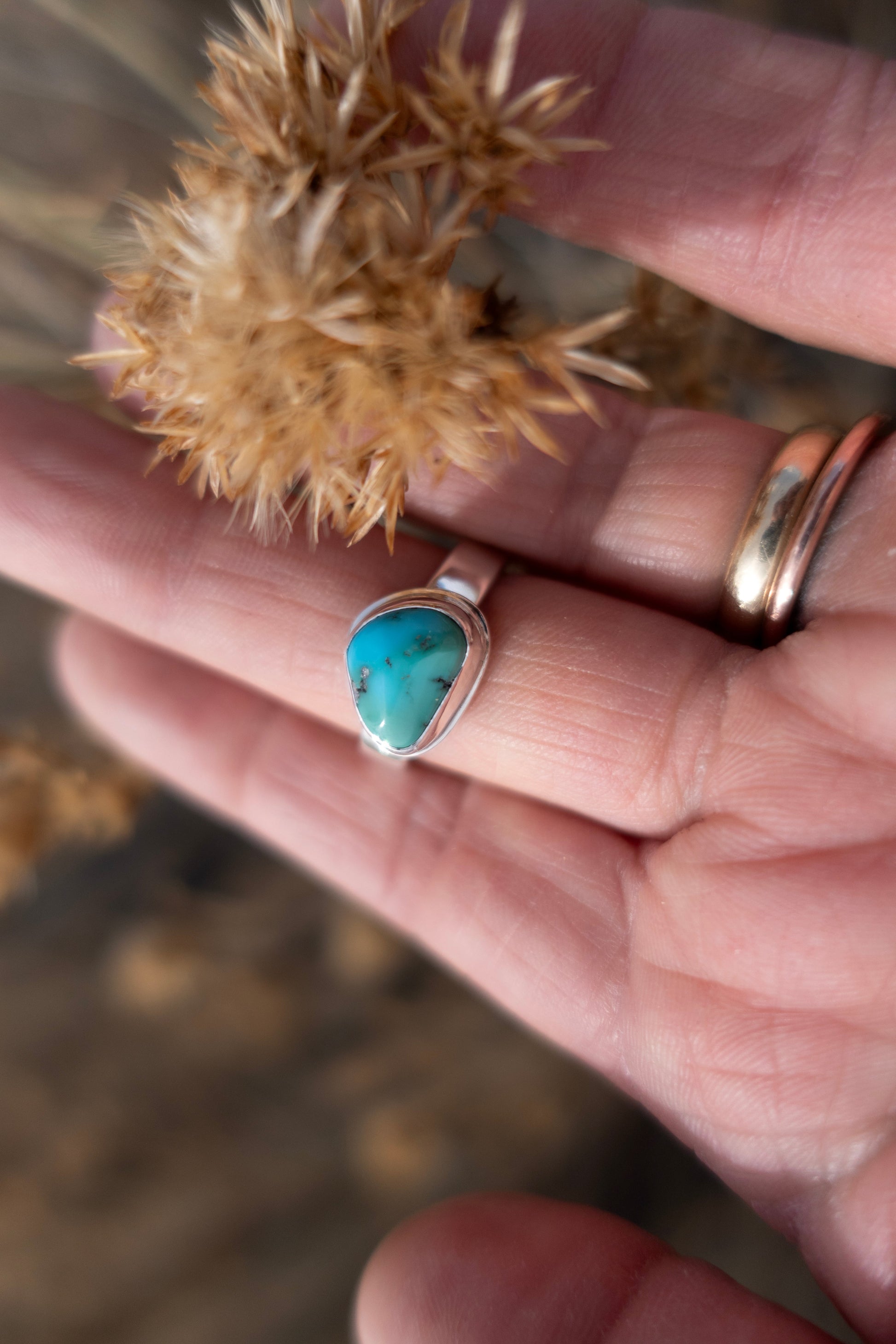 Turquoise ring on a hand with a blurred natural background
